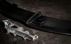 Carbon fiber automotive part next to machined aluminum part on a workbench
