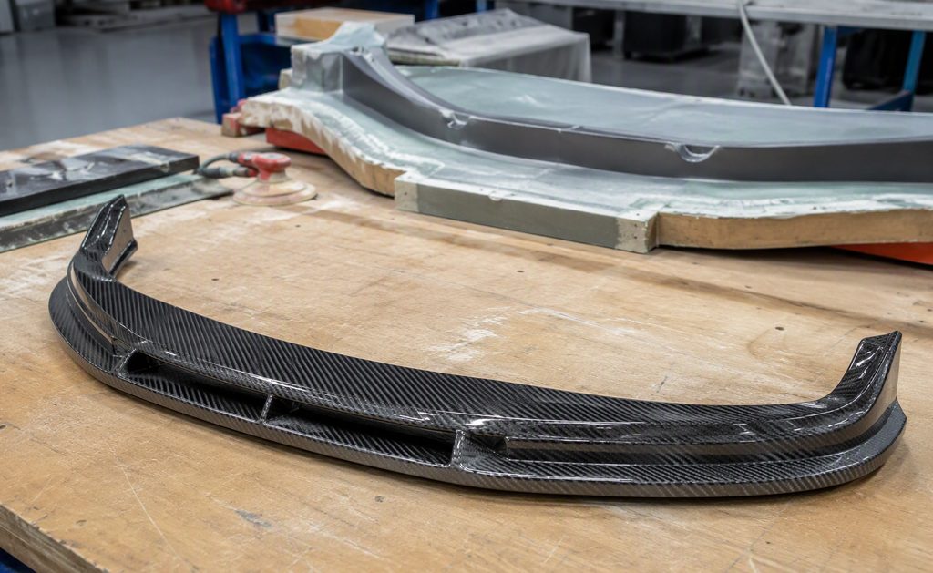 Carbon fiber prototype front lip splitter on a workshop bench
